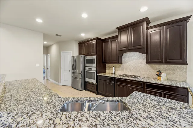 a kitchen with granite countertop wooden cabinets and stainless steel appliances