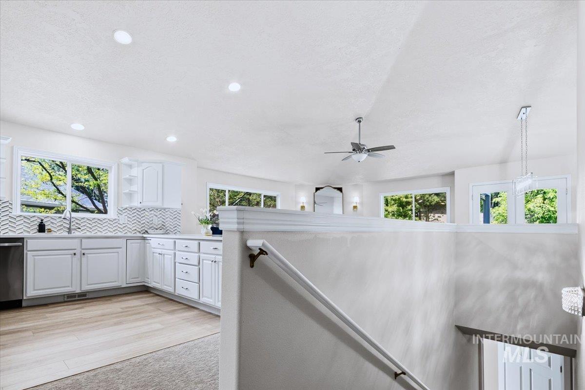 725 North Eagle Road Eagle, ID 83616 - Photo 24 of 45 Modern kitchen featuring white cabinetry, stainless steel appliances, wood-finish flooring, and a chevron tile backsplash