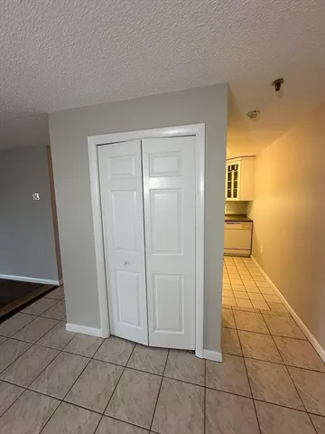 a view of a livingroom with wooden floor and a refrigerator in a kitchen