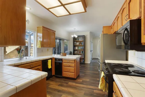a kitchen with stainless steel appliances granite countertop a sink dishwasher a microwave oven with a dining table and chairs with wooden floor