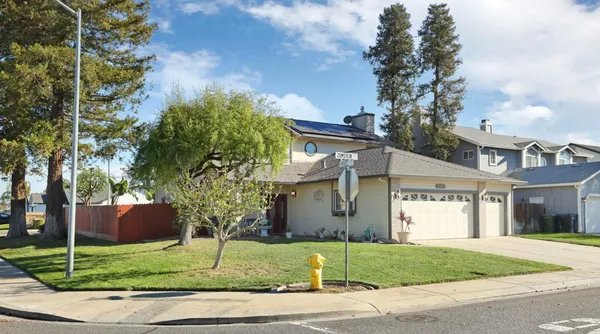 a view of a white house next to a yard and trees