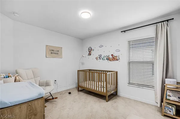 a bedroom with a baby bed a couch and a window