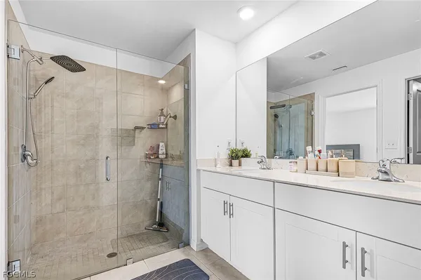 a bathroom with a double vanity sink mirror and shower