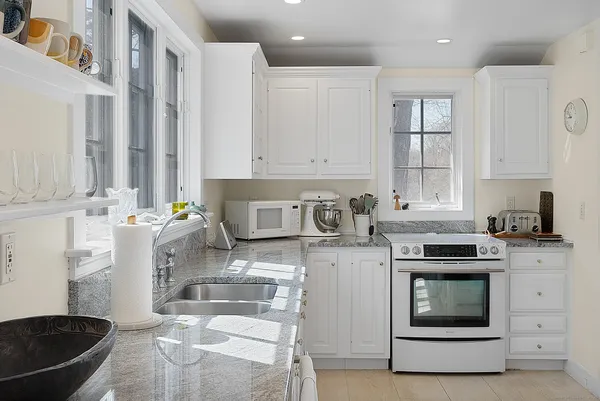 a kitchen with granite countertop a stove sink and cabinets