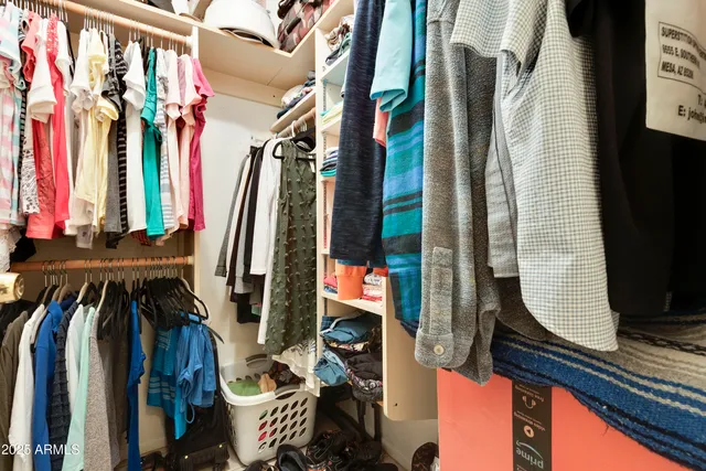 a view of walk in closet with clothes and shoes