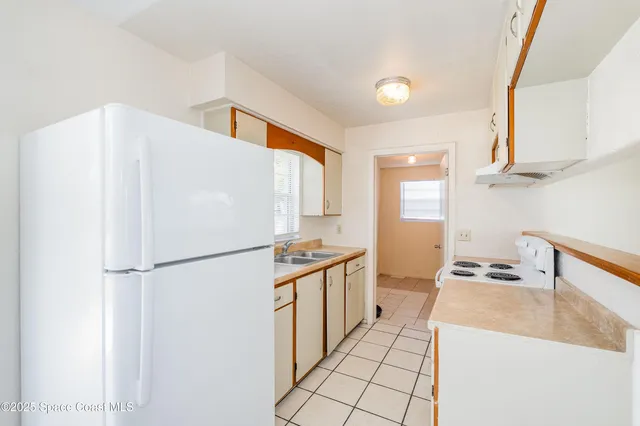 a kitchen with a sink a refrigerator and a stove top oven