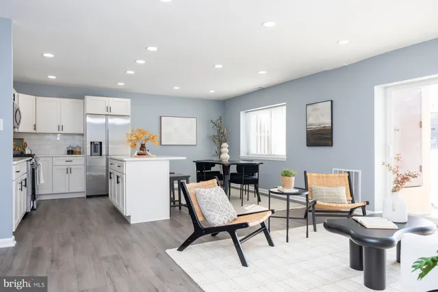a living room with furniture a rug kitchen view and a window
