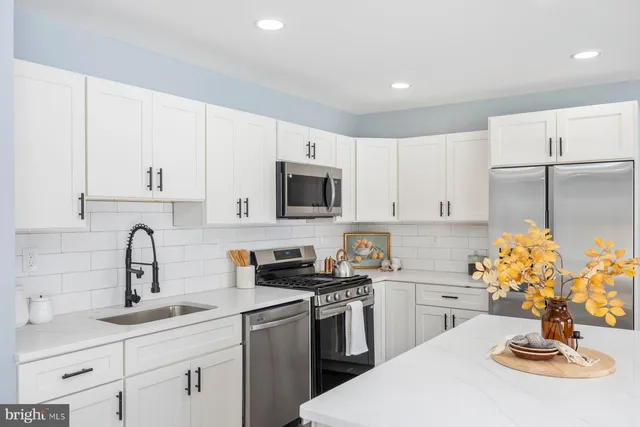 a kitchen with stainless steel appliances a sink a stove a microwave a sink a refrigerator and cabinets