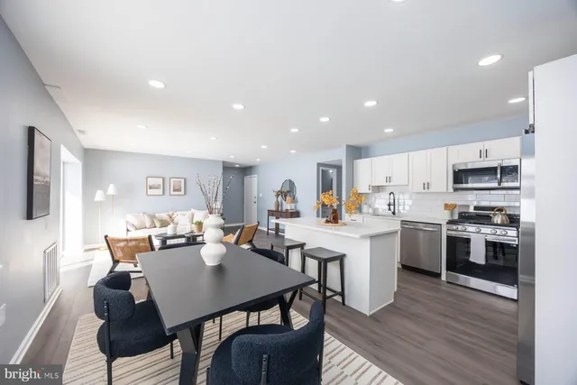 a kitchen with stainless steel appliances kitchen island granite countertop a stove a sink a dining table and chairs