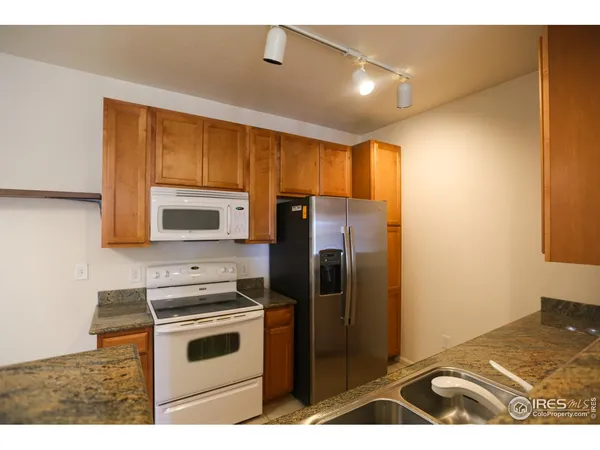 a kitchen with stainless steel appliances granite countertop a refrigerator a stove and a sink with wooden floor