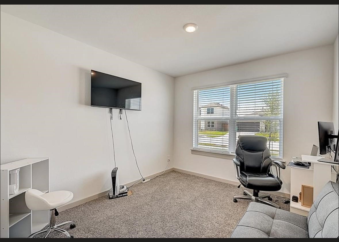 1246 Truckee River Drive Rosharon, TX 77583 - Photo 17 of 23 This room is a bright, carpeted office space with a large window, offering plenty of natural light. It includes a mounted TV, a desk with a computer, and comfortable seating, making it ideal for work or leisure.