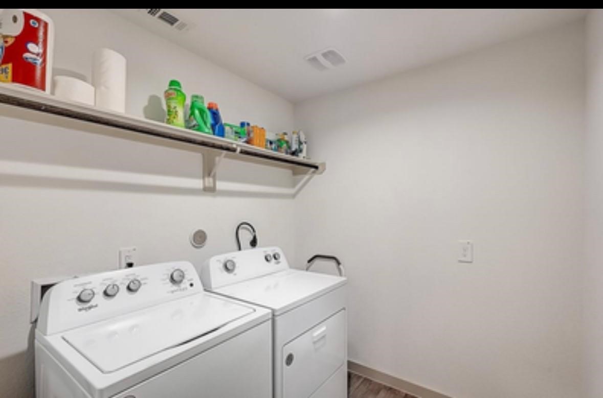 1246 Truckee River Drive Rosharon, TX 77583 - Photo 20 of 23 This photo shows a laundry room with a washer and dryer set against a wall. Above them, there's a shelf stocked with cleaning supplies and paper products, providing ample storage space. The room has a clean, bright appearance with white walls and a simple, functional layout.