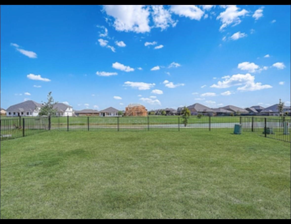 1246 Truckee River Drive Rosharon, TX 77583 - Photo 23 of 23 Spacious fenced backyard with well-maintained grass, offering open views of a suburban neighborhood and a clear blue sky, perfect for outdoor activities and relaxation.