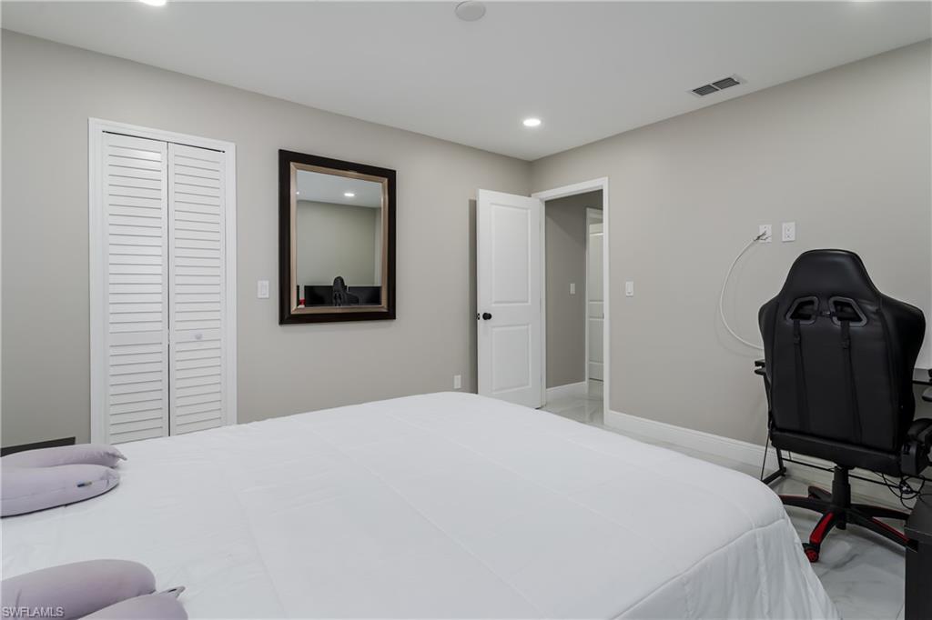 5170 19th Court Southwest Naples, FL 34116 - Photo 18 of 32 a bedroom with a bed and a chair