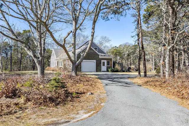 a front view of a house with a yard outdoor seating and covered with trees