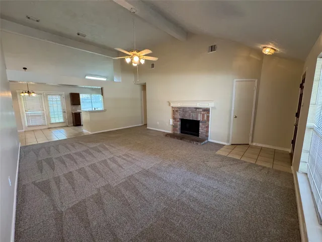 a view of a livingroom with a fireplace a chandelier fan and windows