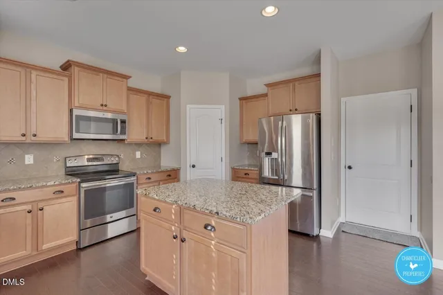 a kitchen with stainless steel appliances granite countertop a stove a refrigerator and a sink with wooden floor
