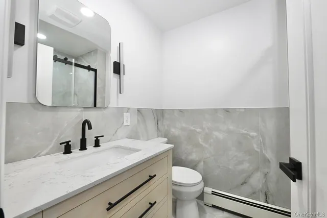 a bathroom with a shower sink vanity mirror and toilet
