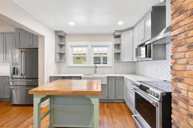 a kitchen with a refrigerator stainless steel appliances wooden floor and cabinets