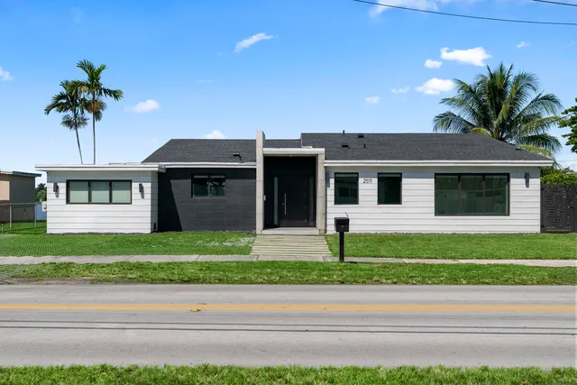 a front view of a house with a garden and plants