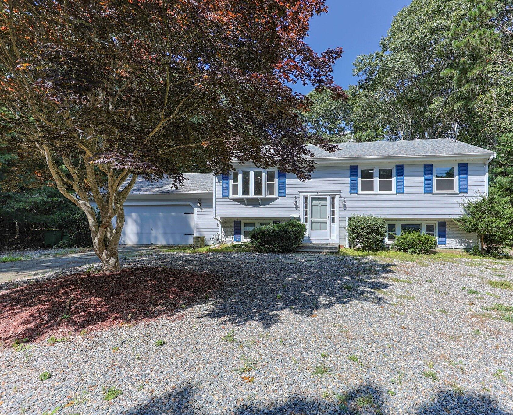 87 Fuller Road Centerville, MA 02632 - Photo 2 of 33 a front view of a house with a dirt yard and a large tree