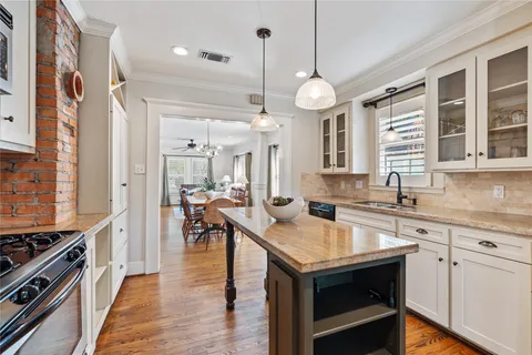 a kitchen with a stove center island a wooden floor and cabinets