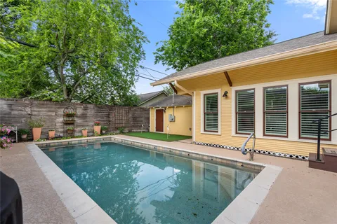 a view of a house with pool chairs and wooden fence