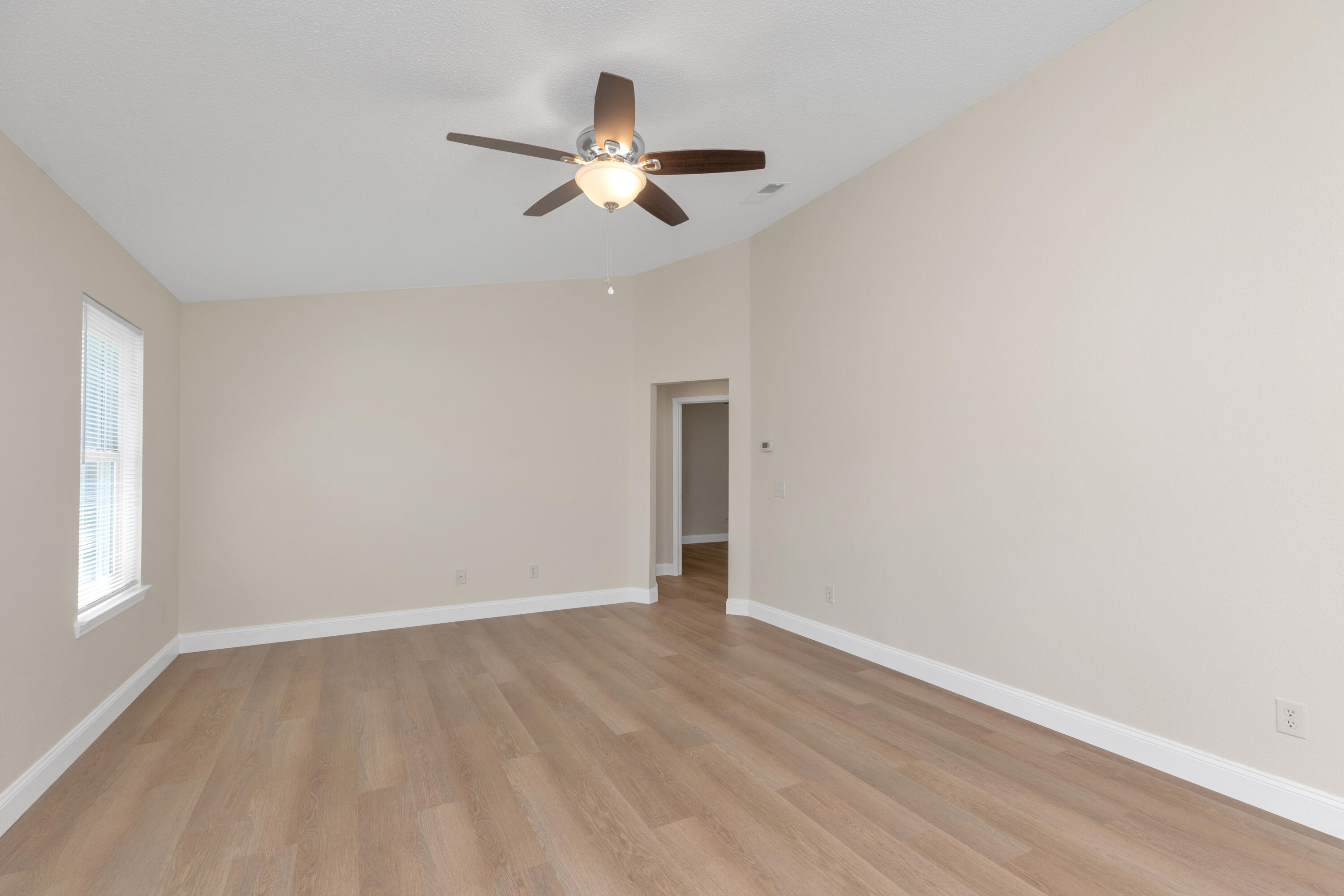 203 Riverchase Boulevard Crestview, FL 32536 - Photo 7 of 36 an empty room with wooden floor fan and window