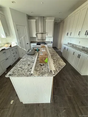 a view of a kitchen with kitchen island white cabinets and wooden floor