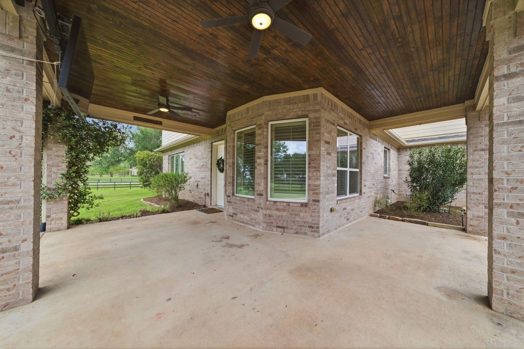 4535 Box Turtle Lane Fulshear, TX 77441 - Photo 44 of 49 Spacious covered patio with a wooden ceiling and ceiling fans, surrounded by a brick exterior. It offers a view of a lush green yard, perfect for outdoor fun!