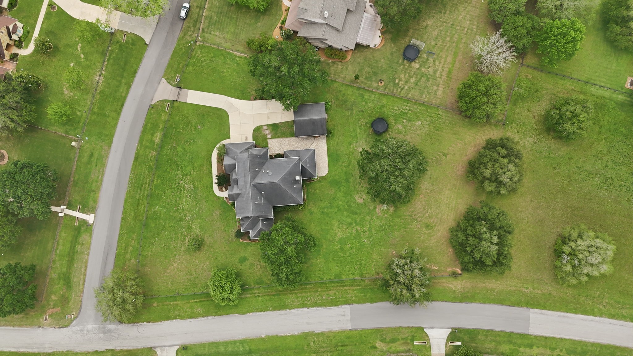 4535 Box Turtle Lane Fulshear, TX 77441 - Photo 47 of 49 This aerial photo showcases the spacious property with a large, well-maintained house and expansive green lawns. The home is located at a corner with curved driveways and is surrounded by mature trees, providing privacy and scenic views.