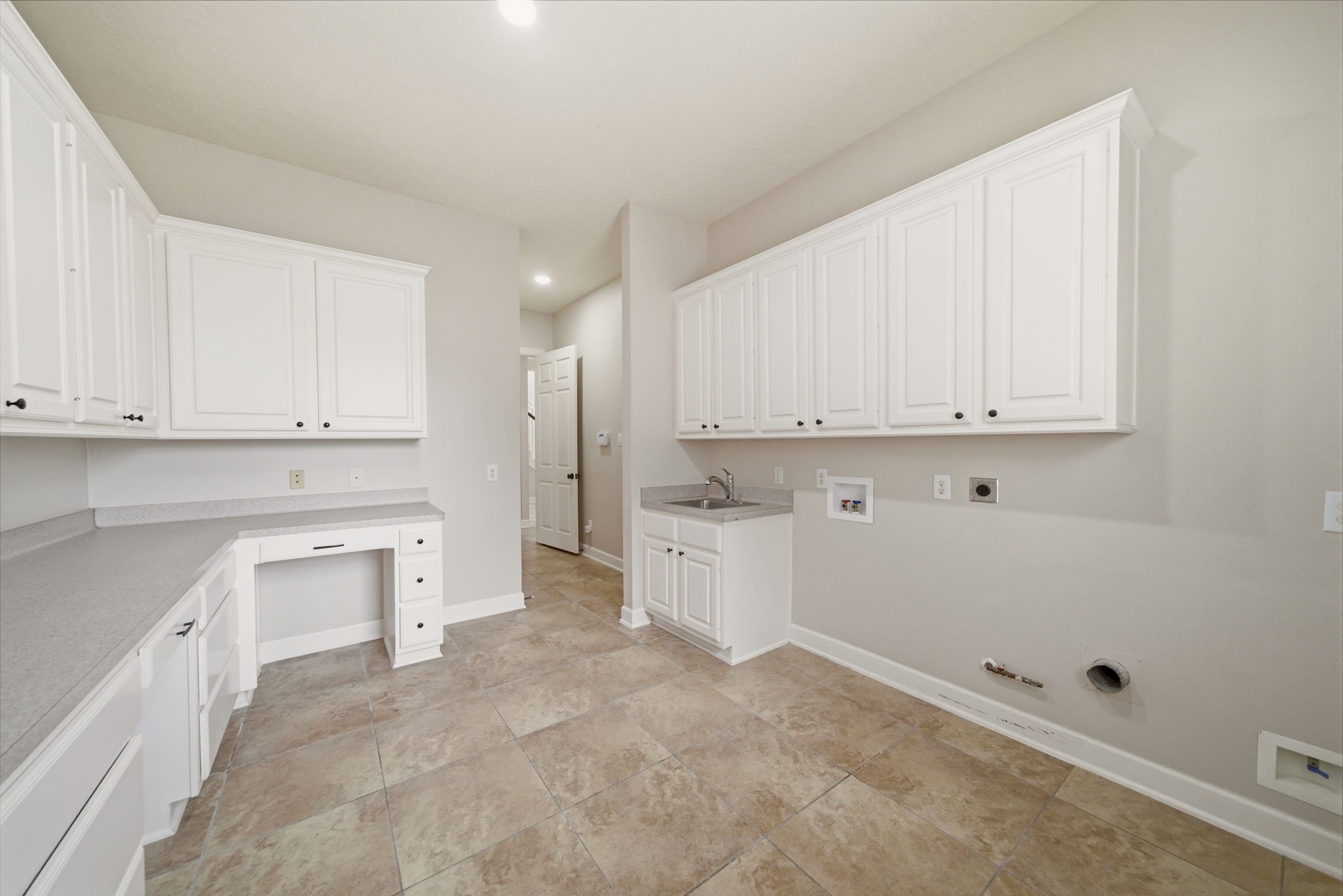 4535 Box Turtle Lane Fulshear, TX 77441 - Photo 6 of 49 Spacious laundry room with ample white cabinetry for storage, a utility sink, and connections for a washer and dryer. The neutral tile flooring and walls create a clean, bright atmosphere.