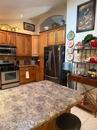 a kitchen with stainless steel appliances granite countertop a refrigerator a stove and a sink with wooden cabinets