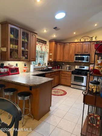 a kitchen with stainless steel appliances kitchen island granite countertop a stove a sink and a microwave