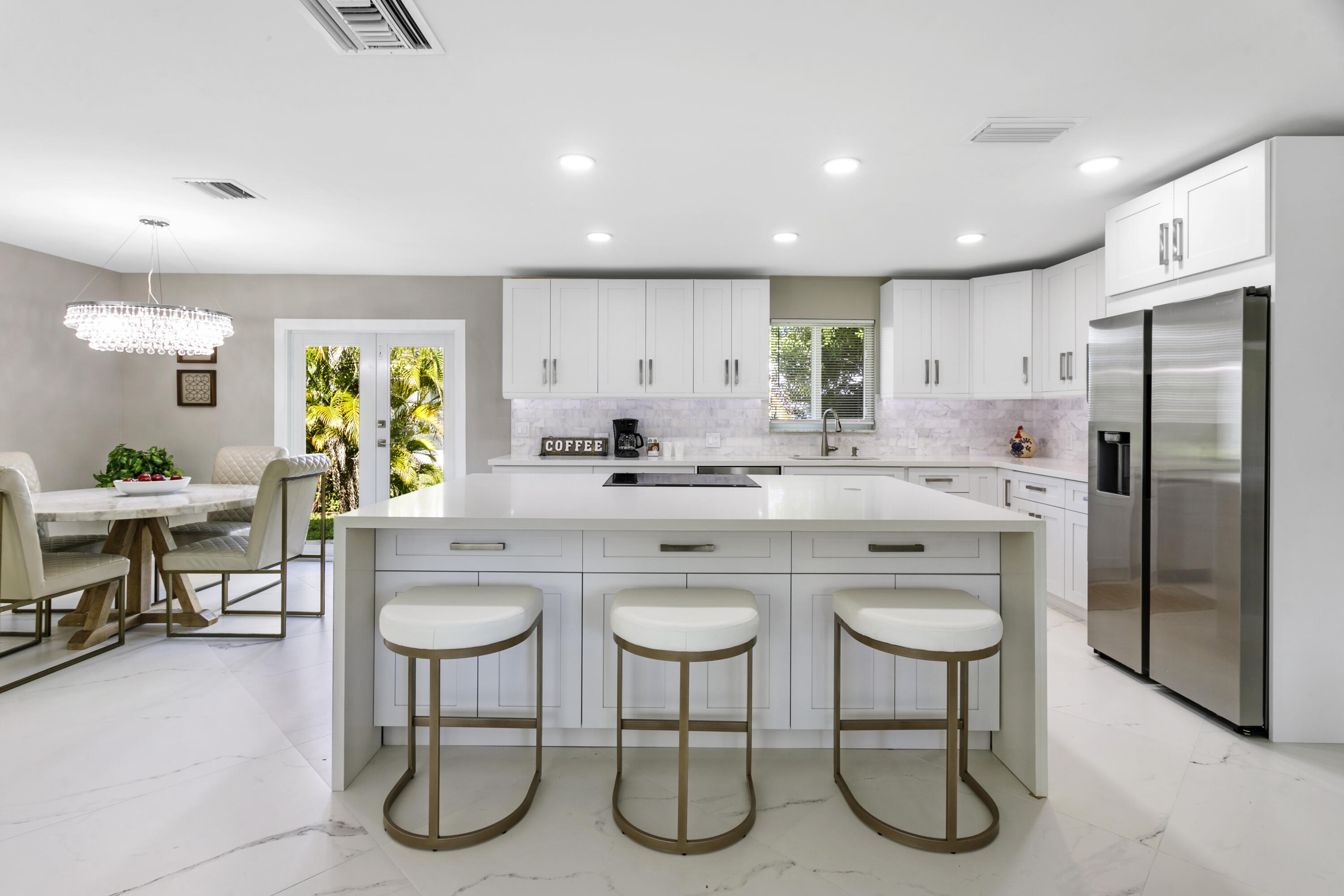 a kitchen with stainless steel appliances granite countertop a table chairs sink and cabinets