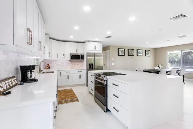 a kitchen with stainless steel appliances granite countertop a table chairs sink and cabinets