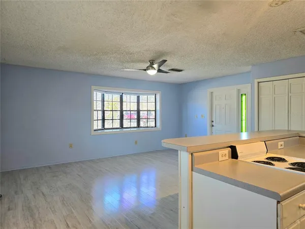 a living room with stainless steel appliances granite countertop a sink a stove and a window