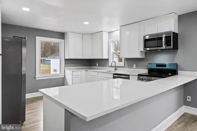 a kitchen with stainless steel appliances granite countertop a sink a microwave a refrigerator and white cabinets
