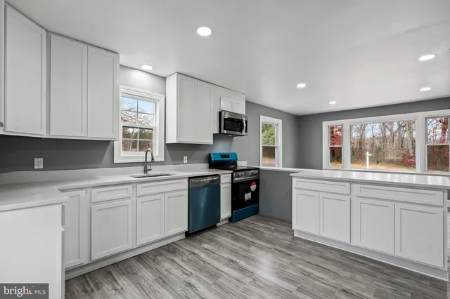 a kitchen with stainless steel appliances granite countertop a stove a sink dishwasher and a microwave oven with white cabinets