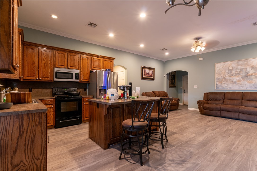 202 Eagle Point Court Waco, TX 76705 - Photo 5 of 14 a kitchen with stainless steel appliances granite countertop a stove top oven a sink dishwasher a dining table and chairs with wooden floor