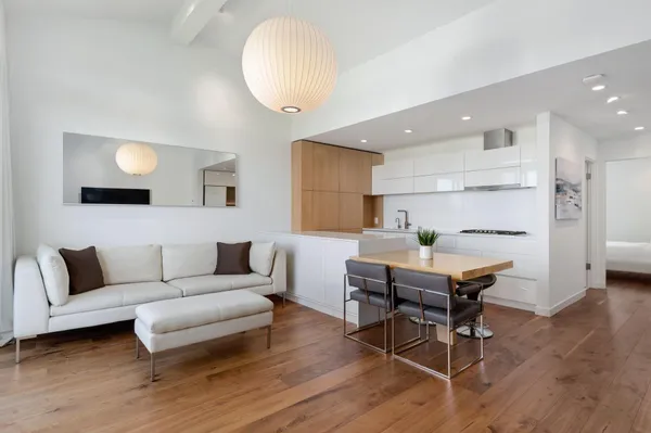 a living room with furniture and a dining table with wooden floor