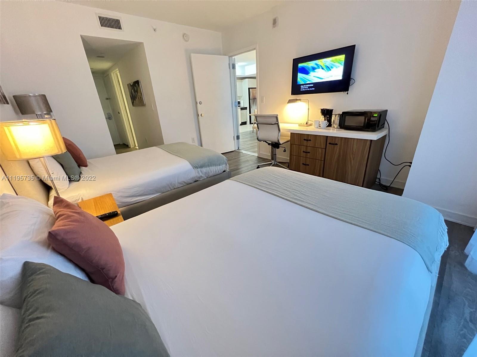 2602 East Hallandale Beach Boulevard, Unit R407 Hallandale Beach, FL 33009 - Photo 33 of 39 a bedroom with a bed and a flat screen tv