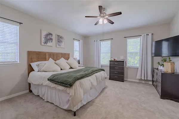 a spacious bedroom with a bed a dresser and a chandelier