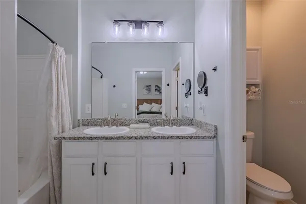 a bathroom with a granite countertop sink a toilet and a mirror
