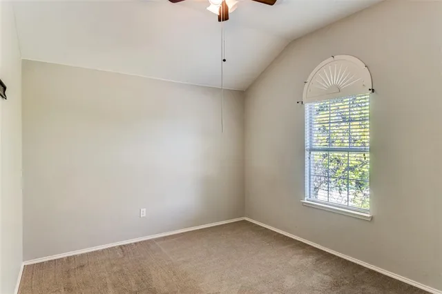 an empty room with chandelier fan and windows
