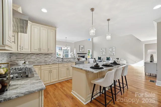 a kitchen with stainless steel appliances kitchen island granite countertop a table chairs in it and white cabinets