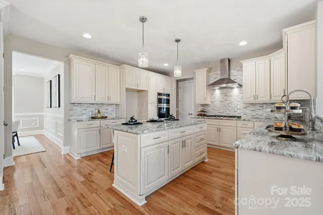 a kitchen with stainless steel appliances white cabinets a sink a stove a refrigerator and white cabinets