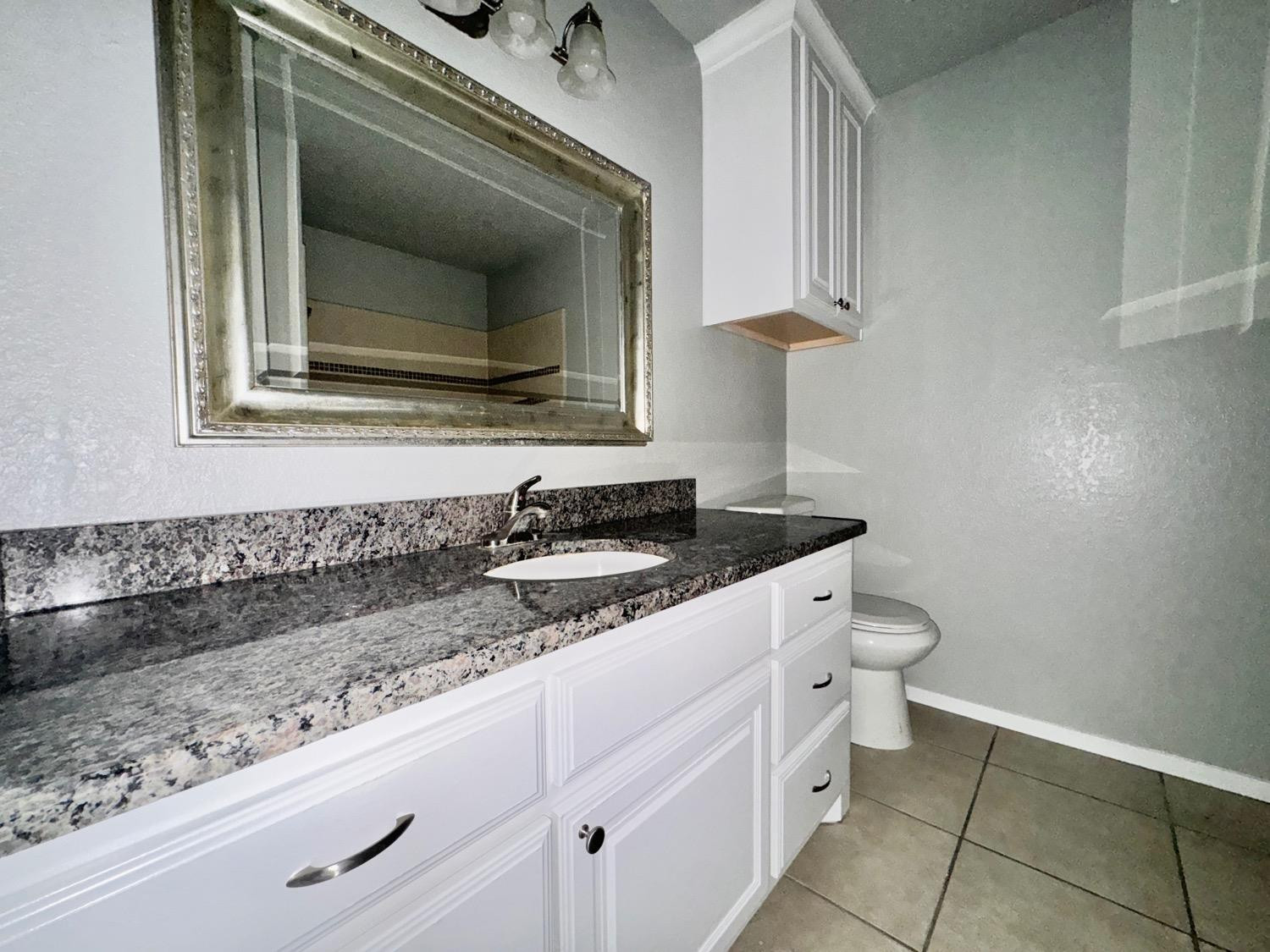 4707 48th Street Lubbock, TX 79414 - Photo 13 of 18 a bathroom with a granite countertop sink and a mirror