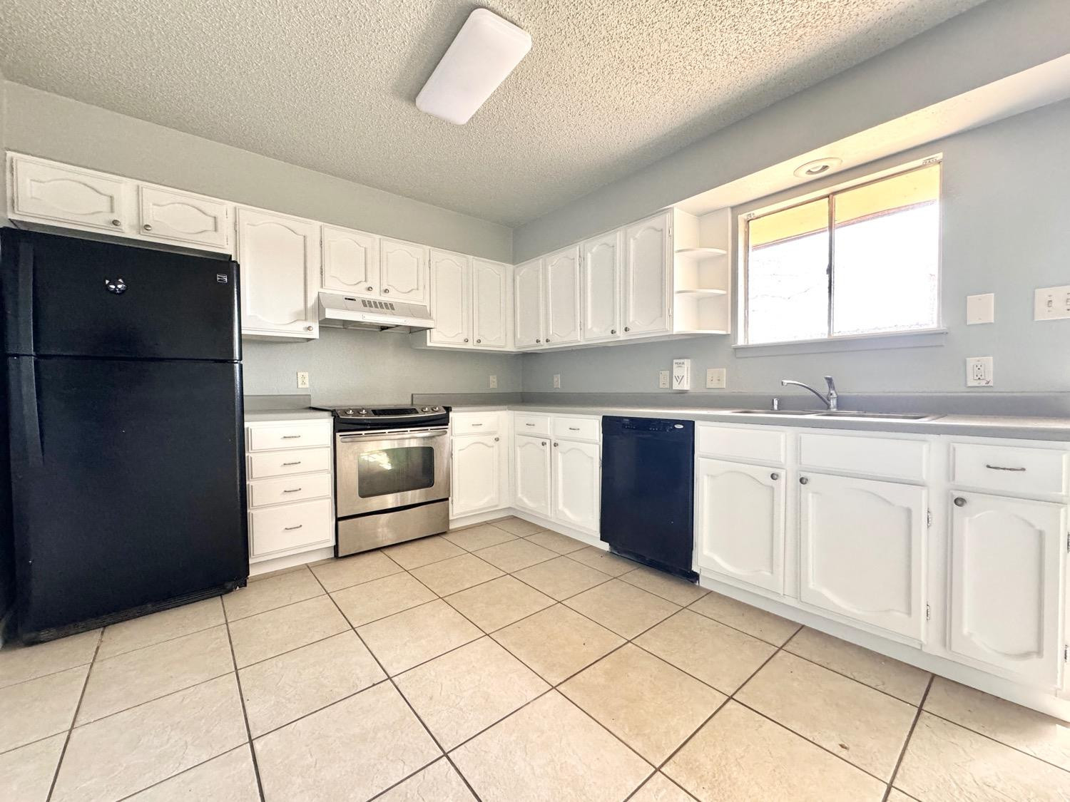 4707 48th Street Lubbock, TX 79414 - Photo 4 of 18 a kitchen with a stove a sink and a refrigerator