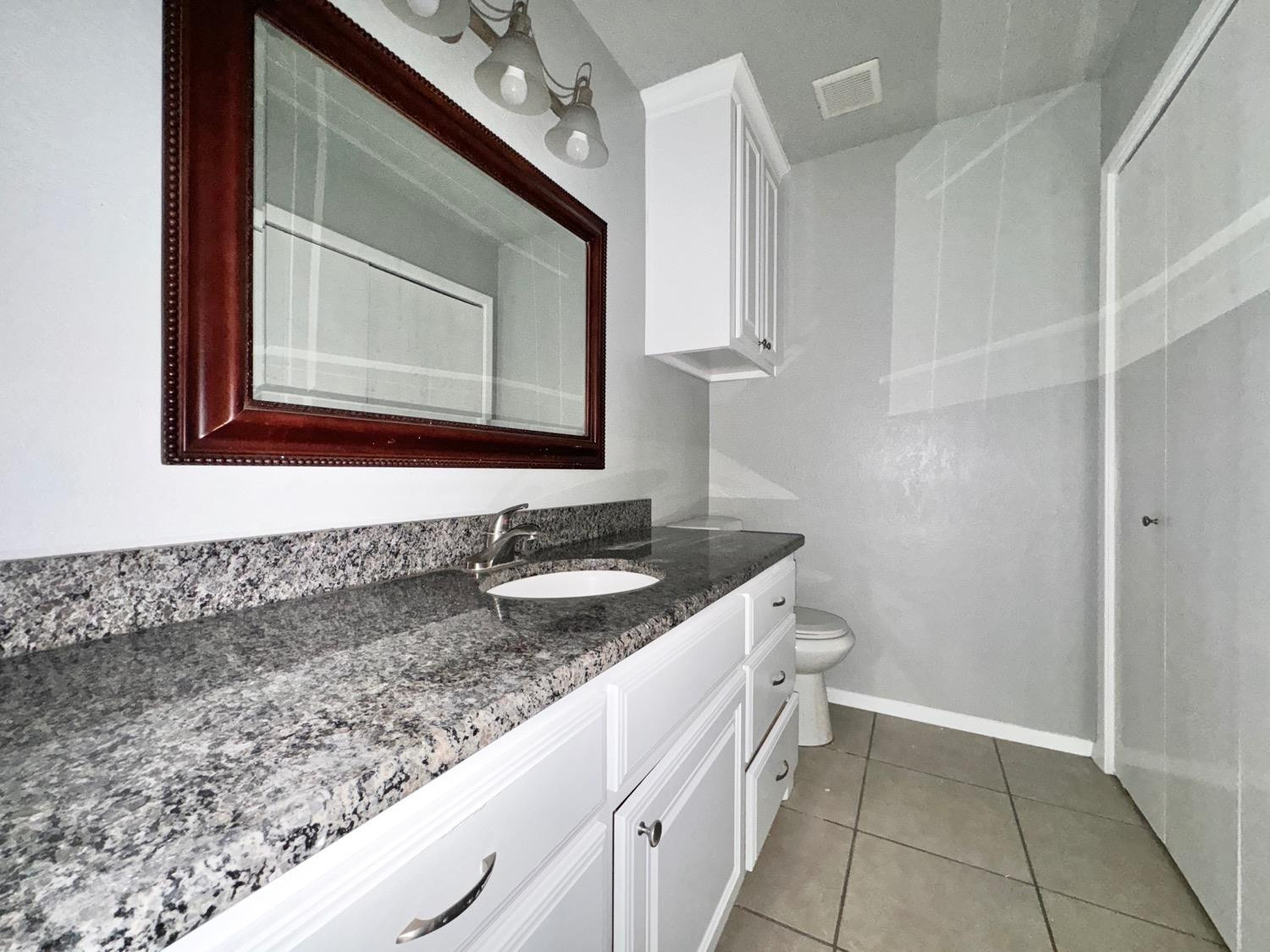 4707 48th Street Lubbock, TX 79414 - Photo 6 of 18 a bathroom with a granite countertop sink and a mirror